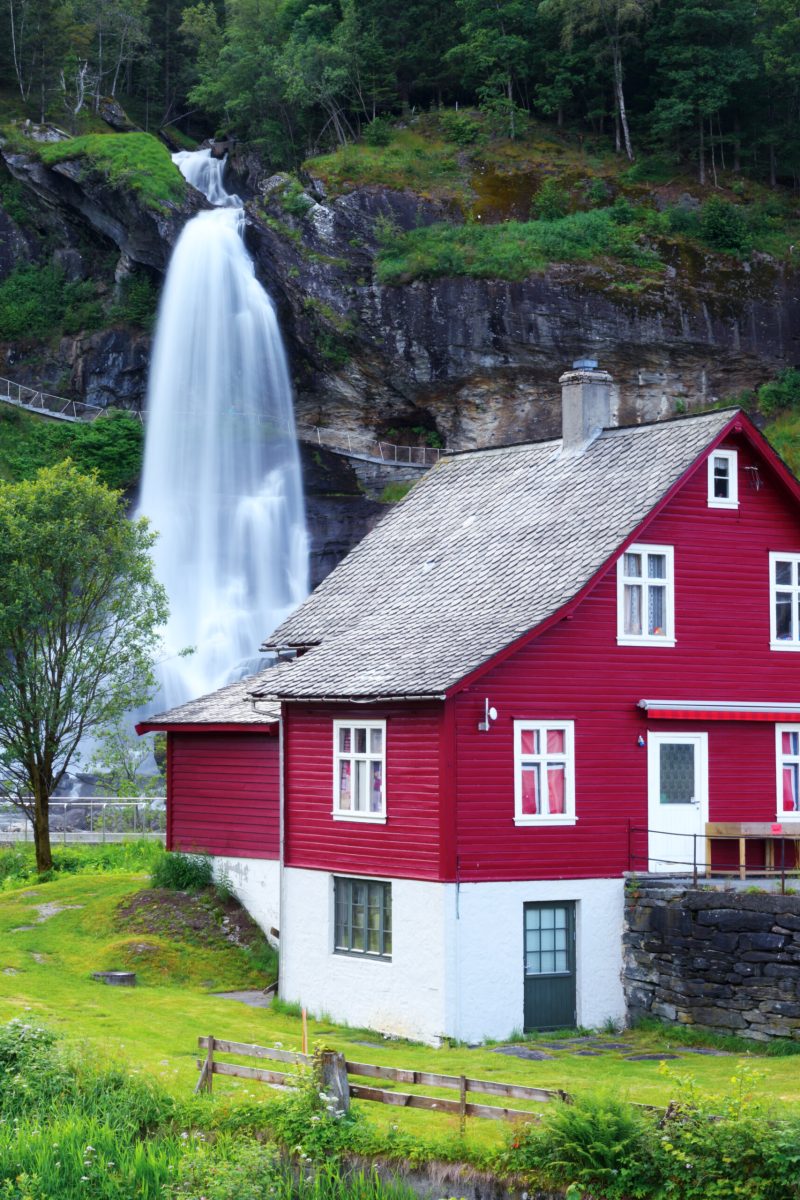 Red house near one of the most popular waterfalls in Norway - Steinsdalsfossen, on the Fosselva river in western Norway